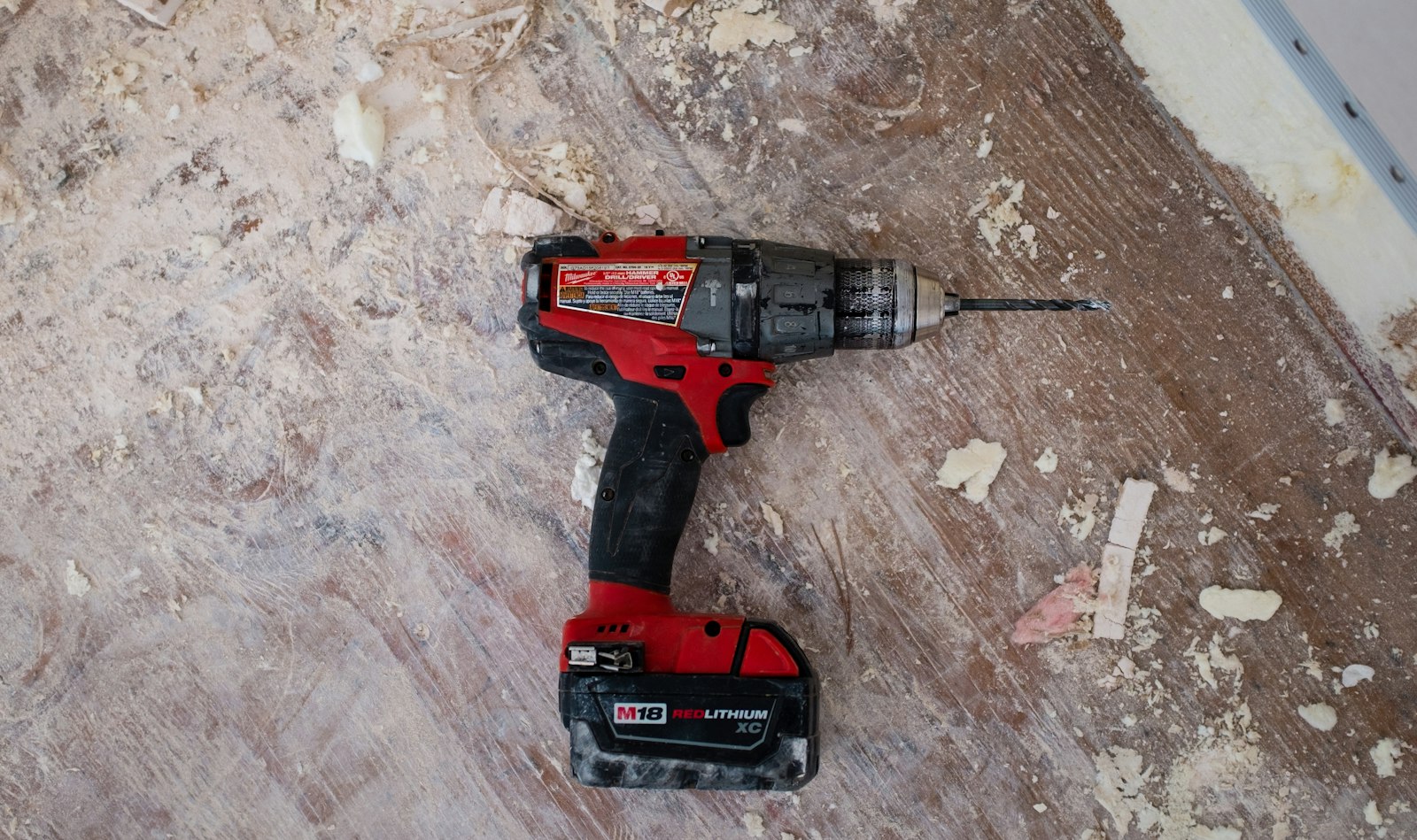 Trapano su un pavimento di legno coperto di trucioli, durante un rinnovo.